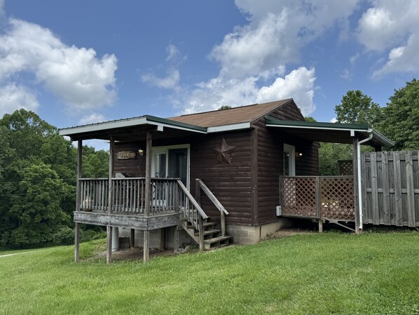A rustic cabin with a porch, a star decoration, and a wooden fence.