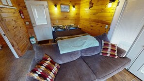 A cozy room with a sofa set, a blanket, and a patterned pillow.