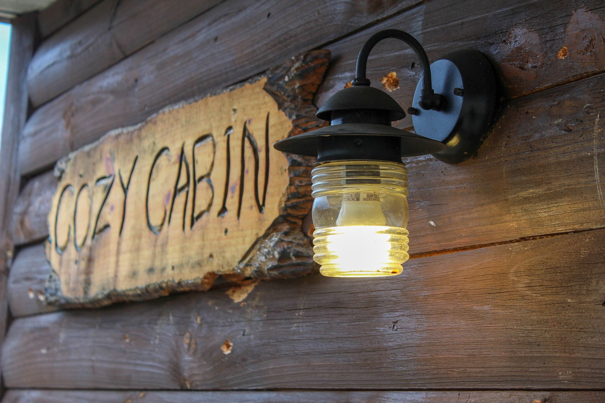 Ein Schild aus Holz mit daran befestigter Laterne.