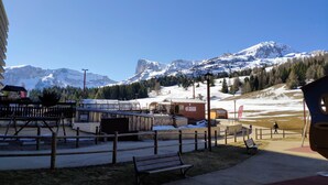Blick auf eine Berglandschaft mit einer hölzernen Bank und einem kleinen Gebäude im Vordergrund.
