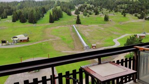 Blick vom Balkon auf eine grüne Landschaft mit einem Gleis, einem kleinen Holzgebäude und einer großen zylindrischen Struktur.