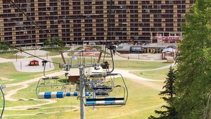 Ein großes, mehrstöckiges Hotel mit einheitlicher Fassade, gelegen in einer gebirgigen Gegend mit Skianlagen.