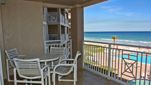 A balcony with a view of the beach and pool, white chairs, and a table. - Bring swim suit and start your beach holiday in this well appointed 2 bedroom 2 bath 3rd floor condo (New Smyrna Beach)