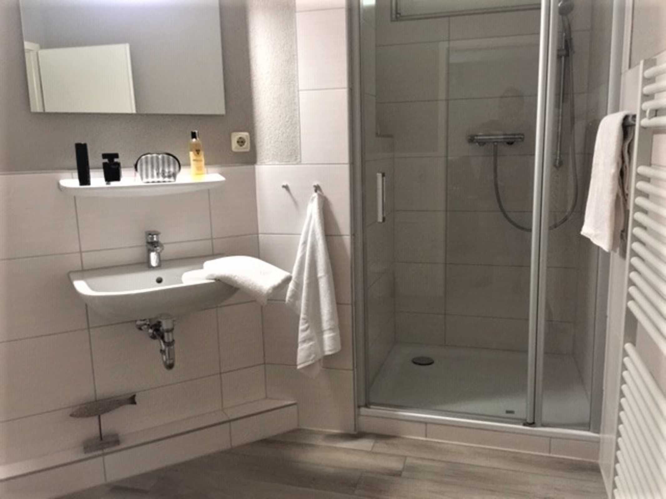 Un baño moderno con cabina de ducha de vidrio, un lavabo con una toalla y un espejo sobre él.