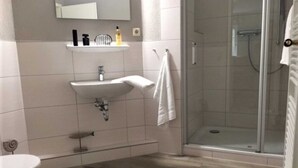 Een badkamer met een wastafel, spiegel en douche.