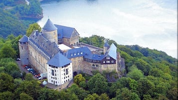 Perched on a forested hillside, this castle offers breathtaking views of a serene lake.