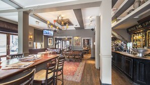 A restaurant with a bar area, wooden tables, and chairs.