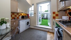 A compact kitchen with a washing machine, a microwave, and a gas stove.