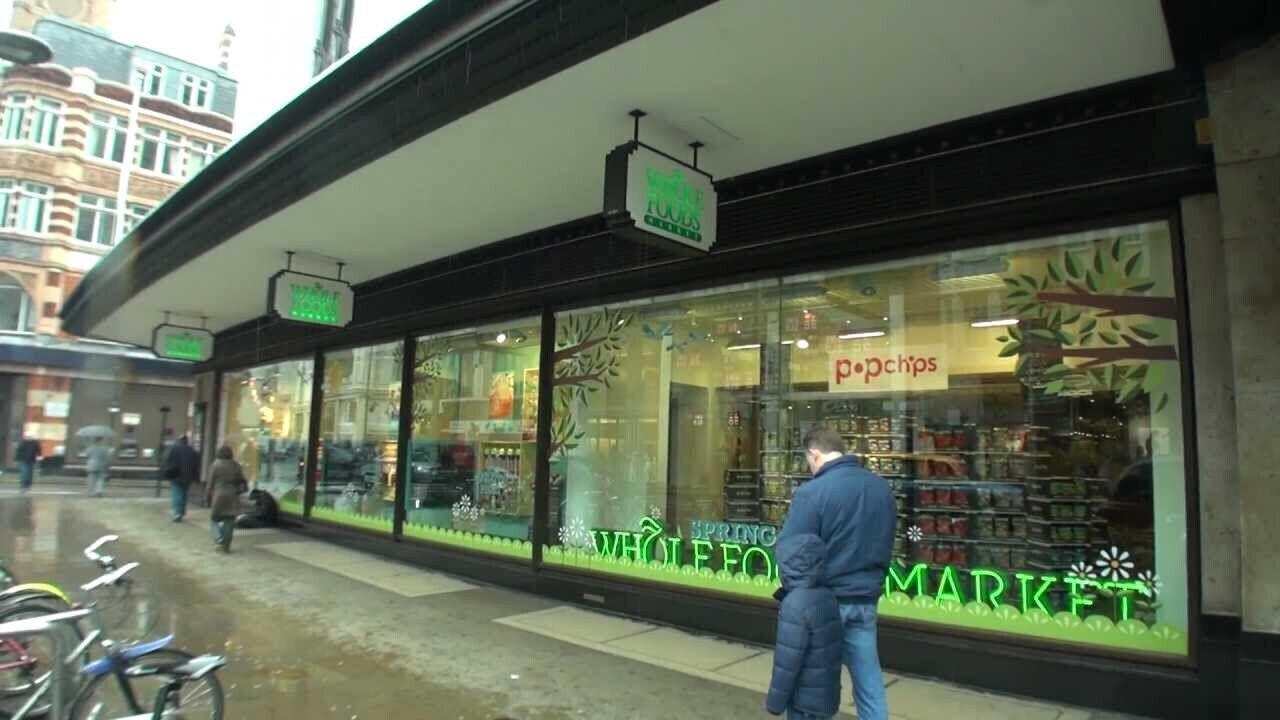 Ein Schaufenster mit einem Schild für 'Whole Foods Market' und 'Popsicles'.