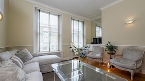 A living room with a sectional sofa, a glass coffee table, two armchairs, and a small side table with a plant.