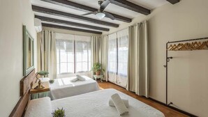 A hotel room with two beds, a ceiling fan, a small table with a lamp, a potted plant, and a coat rack. - La Teja Holiday Home (Marchena)