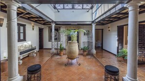 A spacious courtyard with a tiled floor, columns, and potted plants. - La Teja Holiday Home (Marchena)