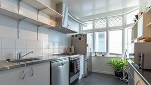 A modern kitchen with white cabinets, stainless steel appliances, and a large window providing natural light.
