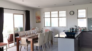 Une cuisine moderne avec un coin repas, de grandes fenêtres et une horloge au mur.