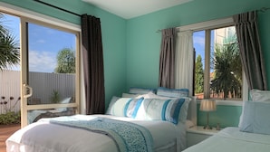 Une chambre avec deux lits, une fenêtre avec des rideaux, une table de chevet avec une lampe, et une vue sur les palmiers à l’extérieur.