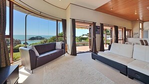 Amplia sala de estar con un gran ventanal que ofrece vistas al mar. Hay dos sofás y una mesita de centro.