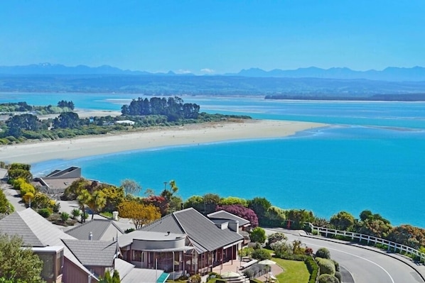 A coastal property with a beach view, a curved road, and a cluster of houses.