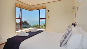 Un dormitorio con un amplio ventanal que ofrece vistas al mar y a las montañas.