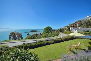 A coastal property with a lawn, a pool, and a view of the sea.