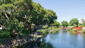 A serene riverside setting with a bridge, trees, and a small water body.