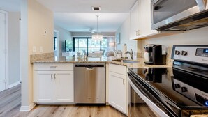 A modern kitchen with white cabinetry, a dishwasher, a stove, and a microwave.