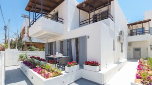 A modern two-story building with balconies, outdoor seating, and flower beds. - Rotunda Suites (Chania)