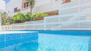 A swimming pool with blue tiles, a white fence, and greenery in the background. - Rotunda Suites (Chania)