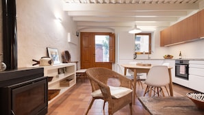 Una cocina con comedor, armarios de madera, una silla de mimbre y piso de baldosas.