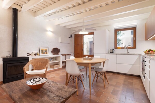 A modern kitchen with white cabinetry, a dining area with a wooden table and chairs, and a black stove.