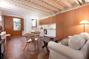 A modern kitchen with wooden cabinets, a dining area with wicker chairs, and a white sofa.