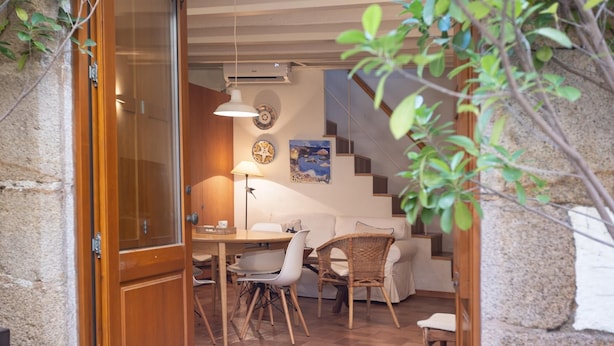Una habitación acogedora con zona de comedor, sofá, escalera y una pared decorada con placas.
