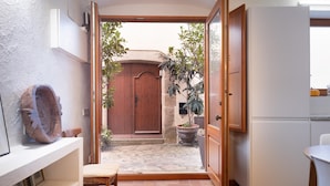 Una cocina con una puerta abierta que da a un patio, una planta en maceta y un banco de madera.