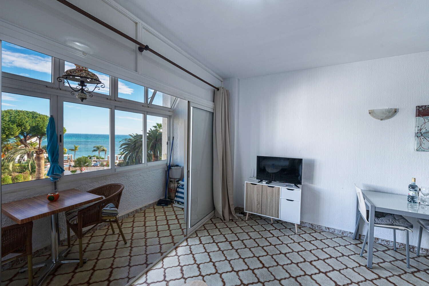 A balcony with a TV, a dining table, and chairs.