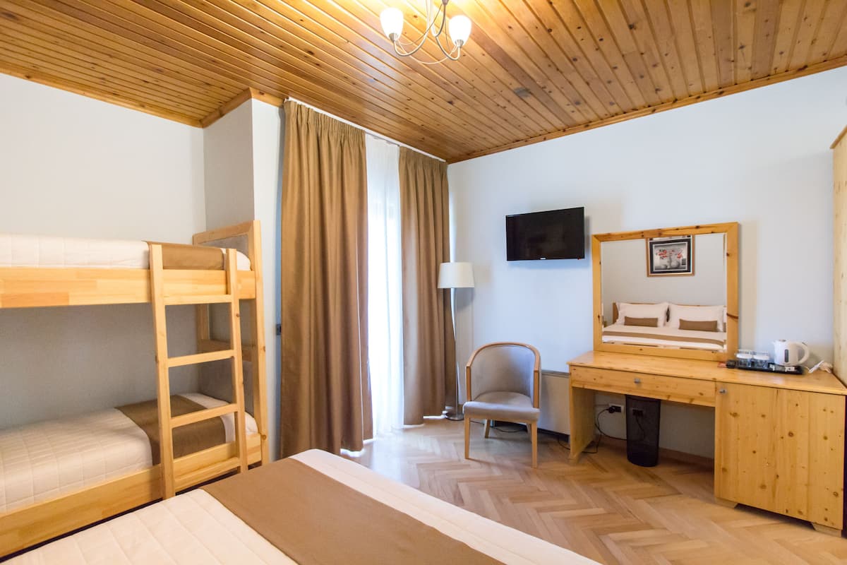 Una habitació amb llits superposats, escriptori, cadira, televisió i mirall.