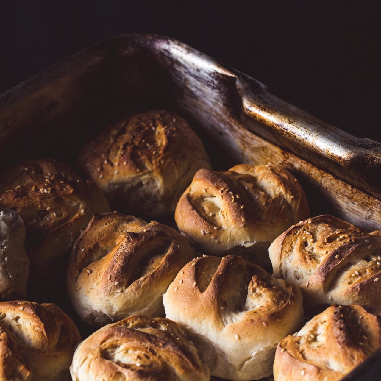 A tray of freshly baked bread rolls with sesame seeds.