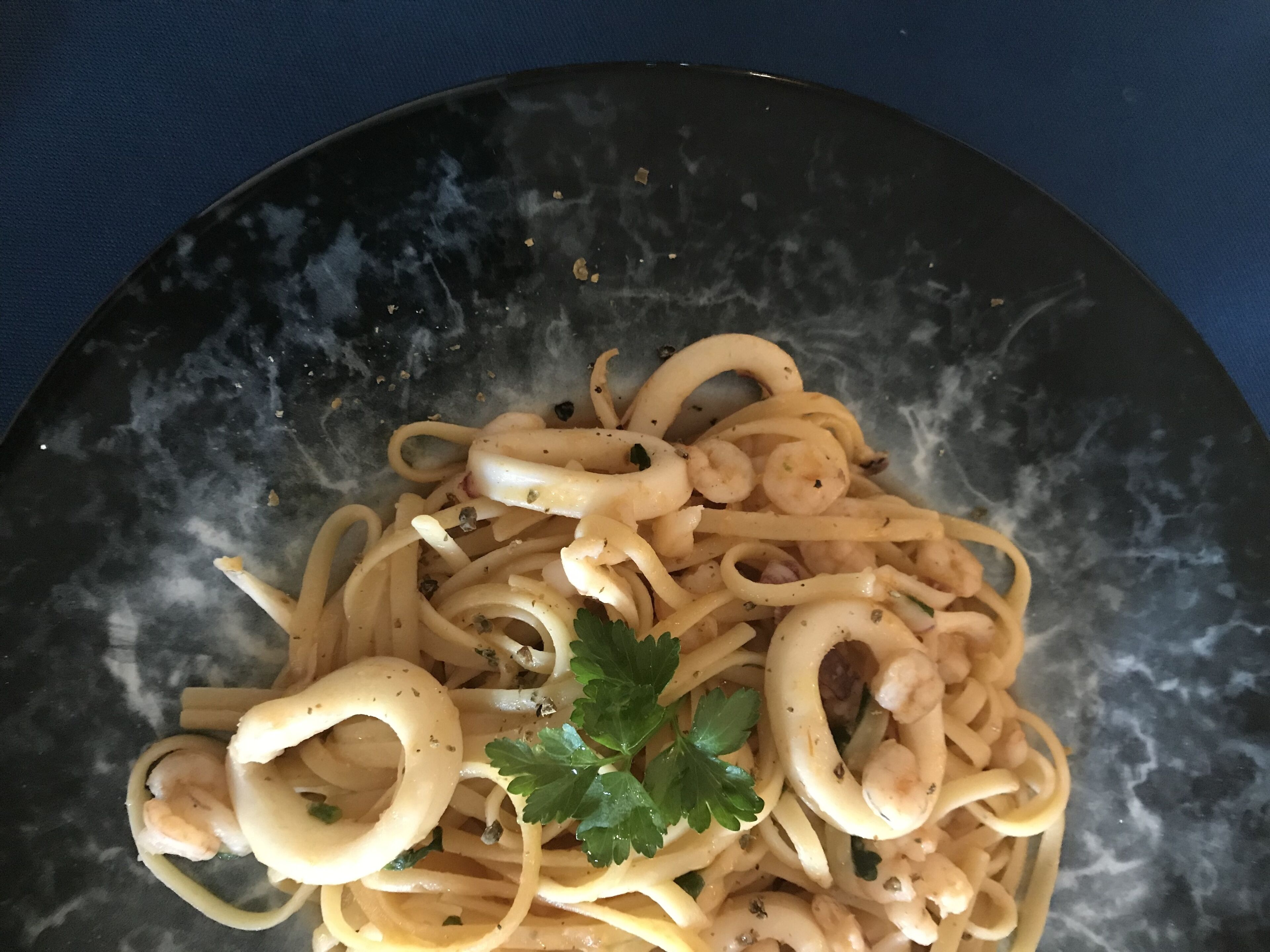 Un plato de pasta con aros de calamar y decoración de perejil.