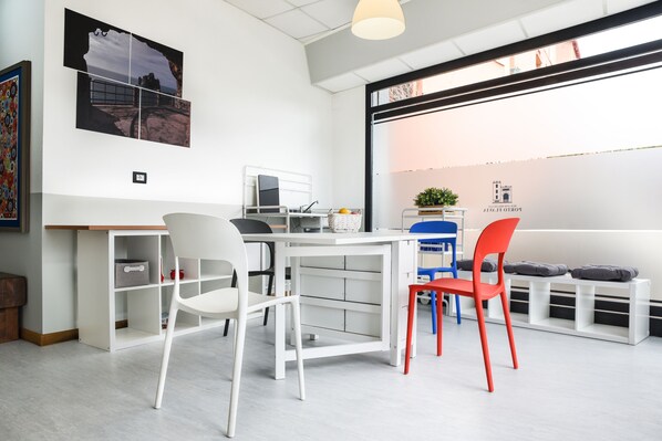 A modern, well-lit room with a white desk, chairs, and a large window.