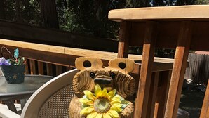 Eine Holzskulptur eines Bären mit einem Sonnenblume auf dem Kopf, platziert auf einem Baumstumpf.