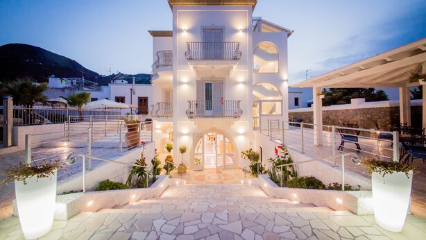 A multi-story building with a central entrance, balconies, and outdoor seating areas. - Odysseus Hotel (Lipari)
