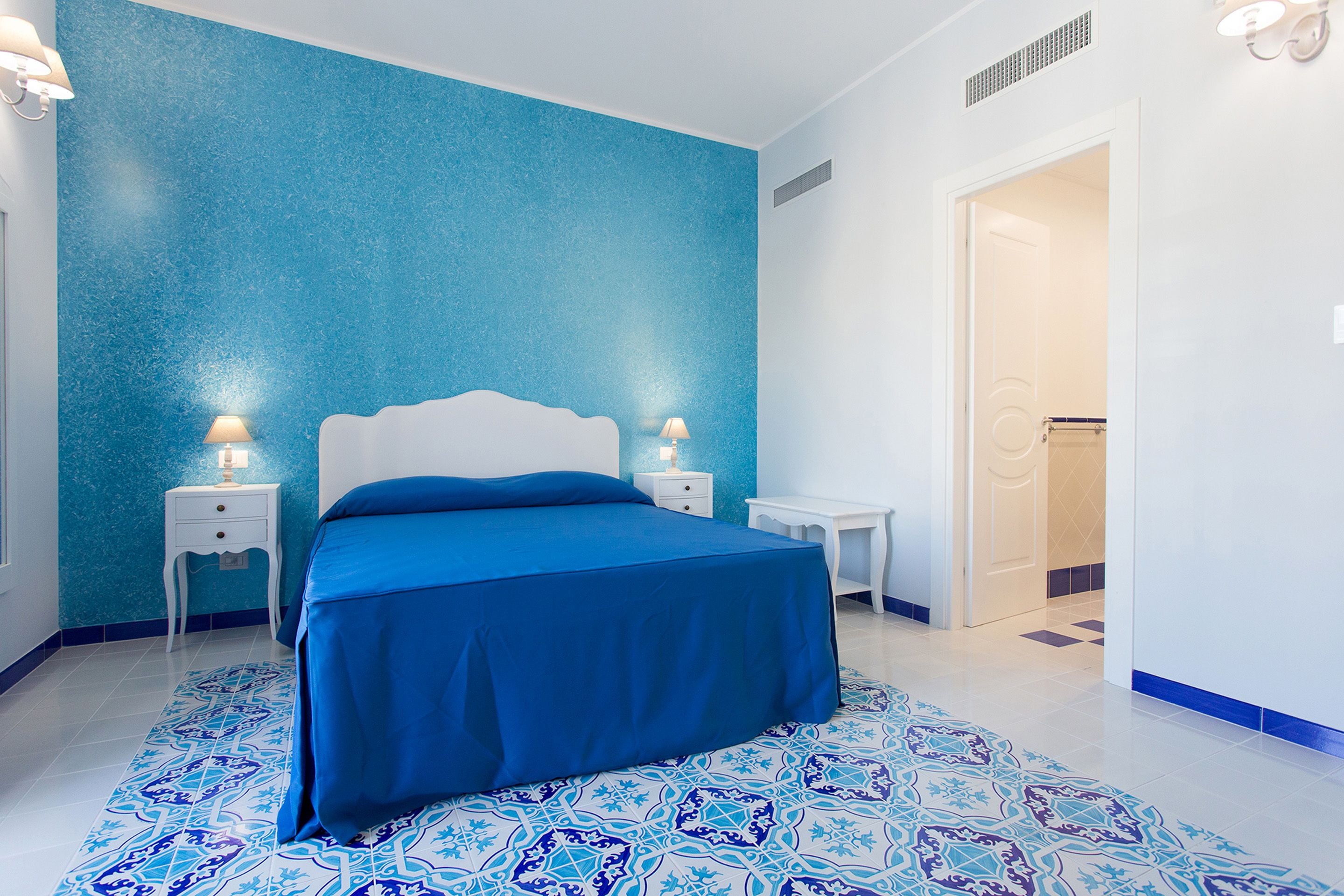 Um quarto com cama, mesas de cabeceira e escrivaninha.