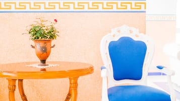Una habitación con una mesa redonda de madera, una planta en maceta, una silla azul y un cuadro en la pared.