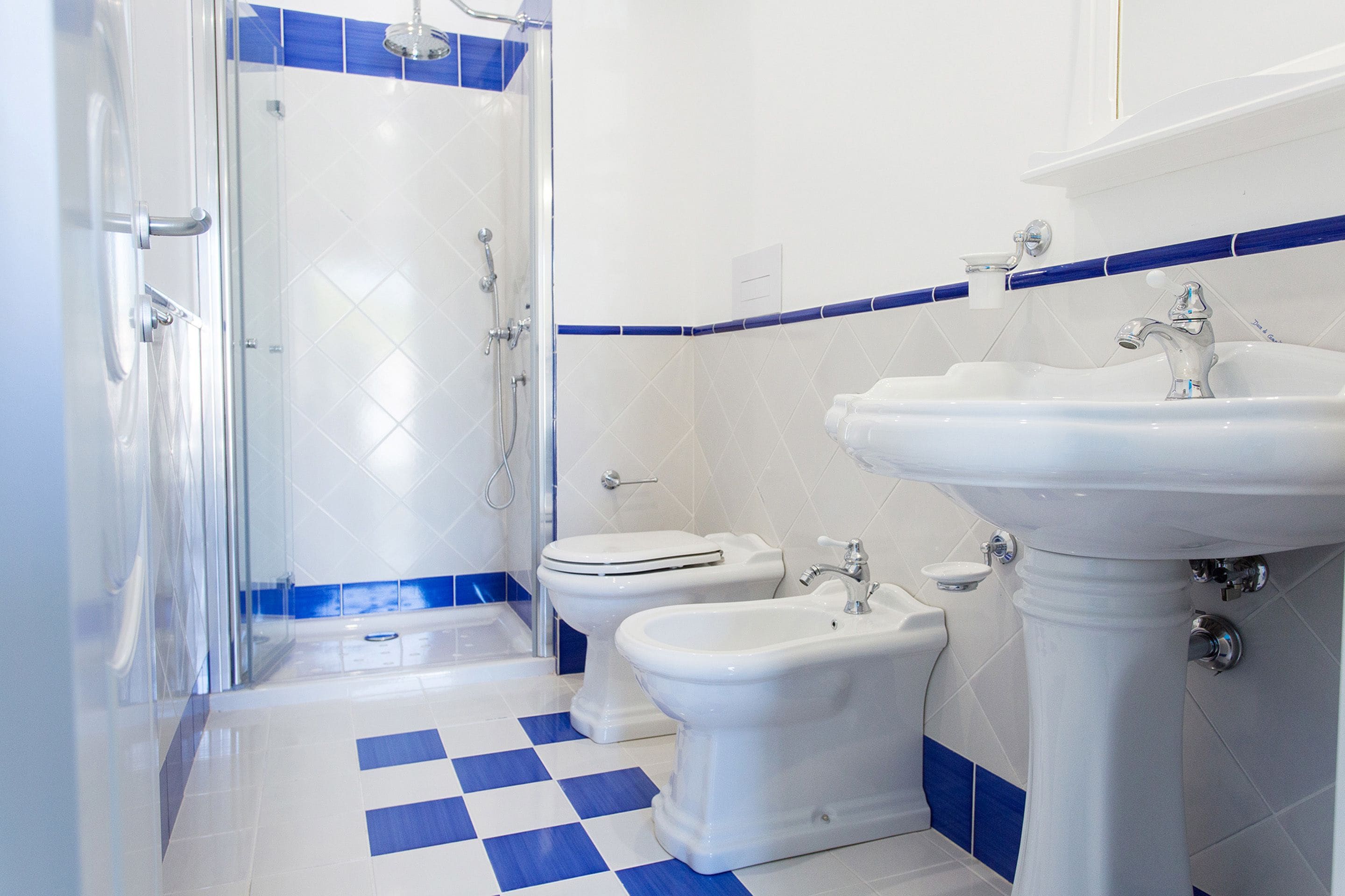 A bathroom with a shower, toilet, bidet, and sink.