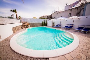 Piscine extérieure en saison, piscine avec cascade, parasols