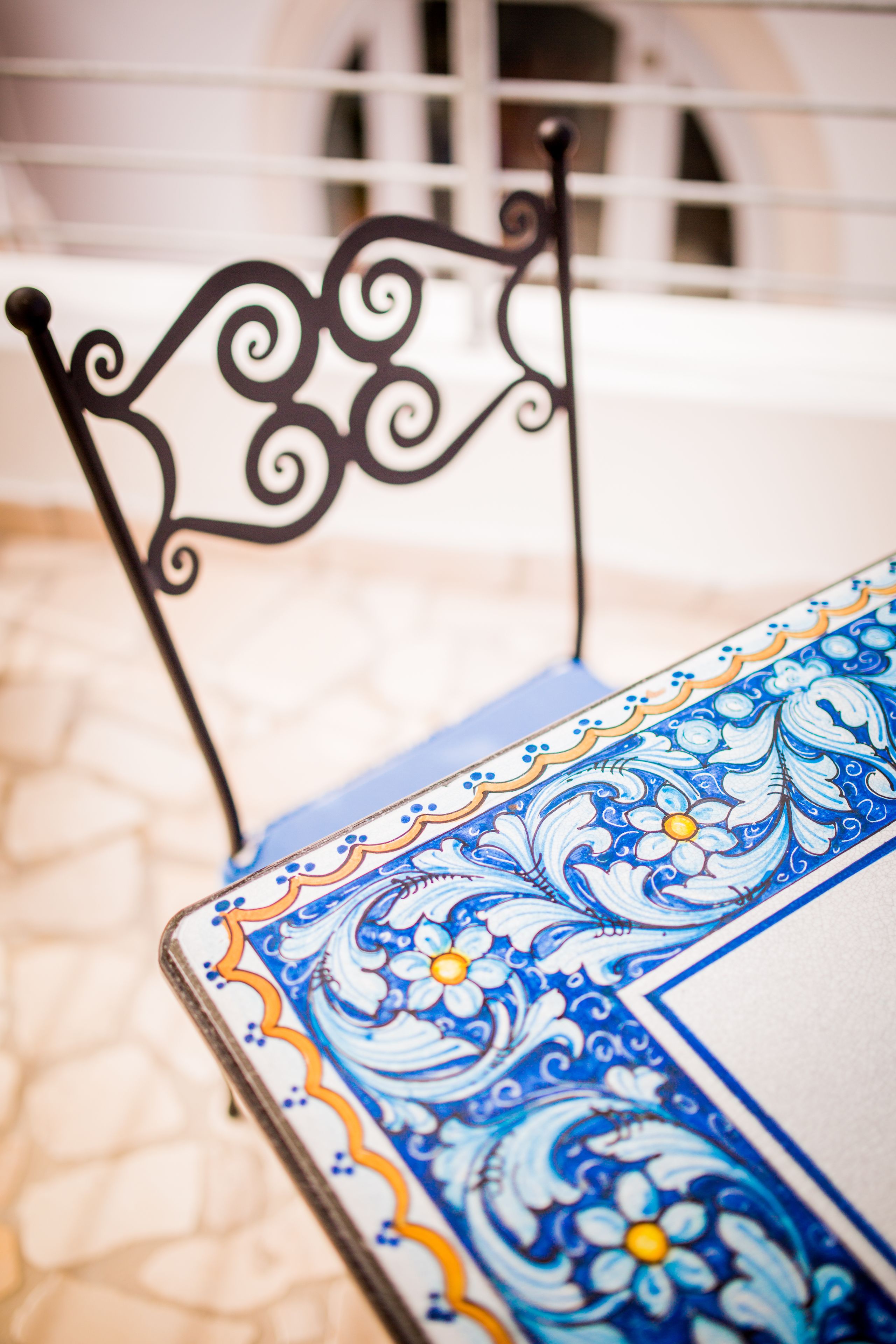 A metal chair with ornate designs and a table with a blue and white floral pattern.