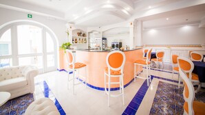 A hotel lobby with a central bar area, seating arrangements, and a white sofa. - Odysseus Hotel (Lipari)