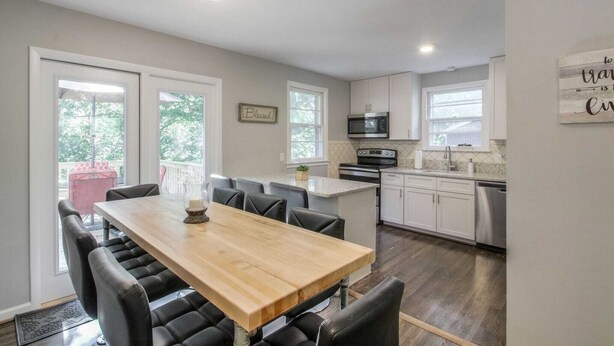 A modern kitchen with white cabinets, a wooden dining table, and a built-in microwave. - Vintage Charm-Wine cellar/bar room, sleeps 12! (Nashville)