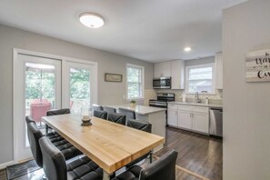 Una cocina moderna con armarios blancos, una mesa de comedor de madera y un microondas integrado.