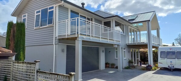 A two-story house with a balcony, garage, and a parked vehicle.