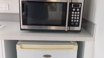 A compact kitchen with a built-in microwave and toaster oven on a white countertop.