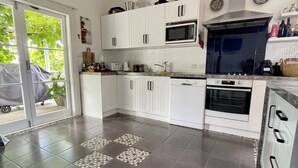 Une cuisine moderne avec des meubles blancs, un four à micro-ondes, un four traditionnel et une cuisinière à gaz.